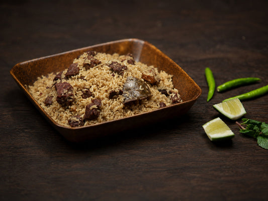Bangladeshi Beef Tehari with garam masala served in a brown bowl with green chili and lime